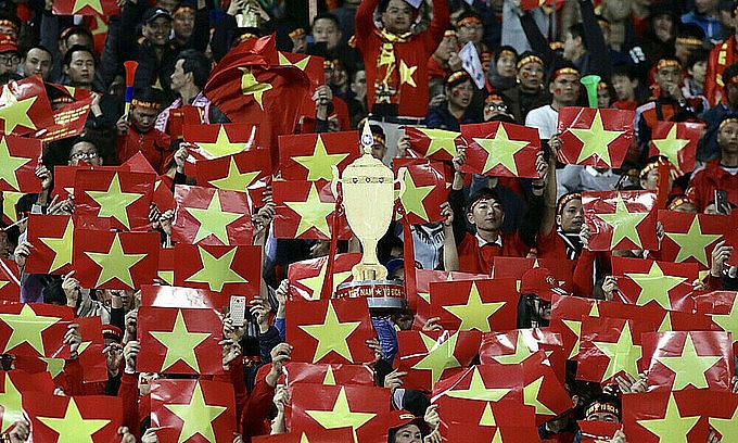 Spectators hold up images of the Vietnamese national flag during the AFF Cup final between Vietnam and Malaysia at My Dinh Stadium in Hanoi, December 15, 2018. Photo: VnExpress