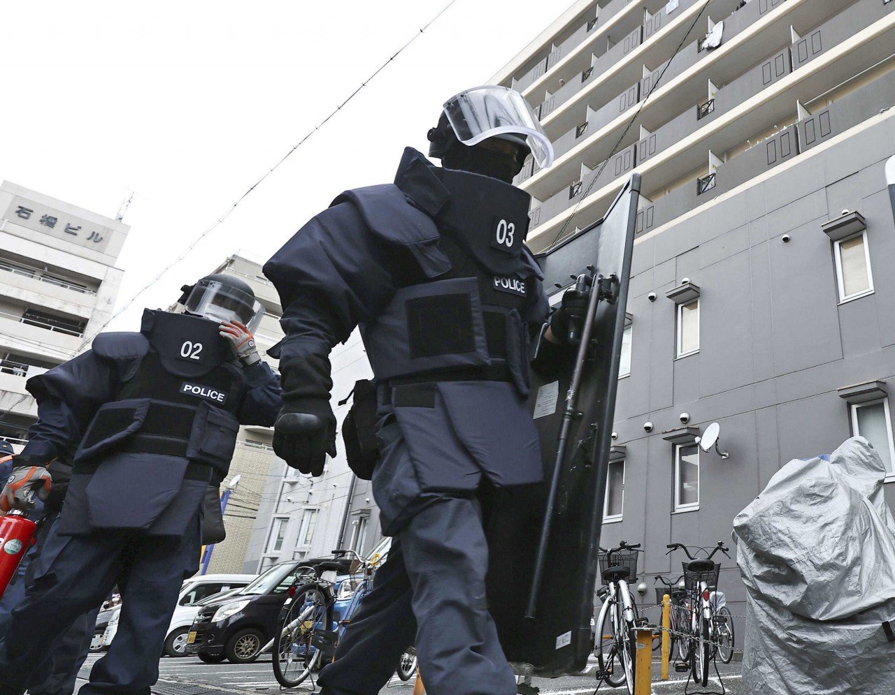 Police investigators head to a condominium owned by the man in custody for the shooting of former Japanese Prime Minister Shinzo Abe in Nara, Japan, on July 8. (Kyodo/Reuters)