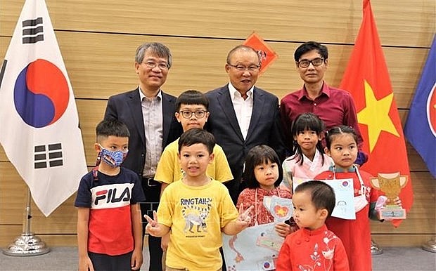 Ambassador Nguyen Vu Tung (left, behind) and coach Park Hang-seo (centre, behind) in a photo with Vietnamese children. Photo: VNA
