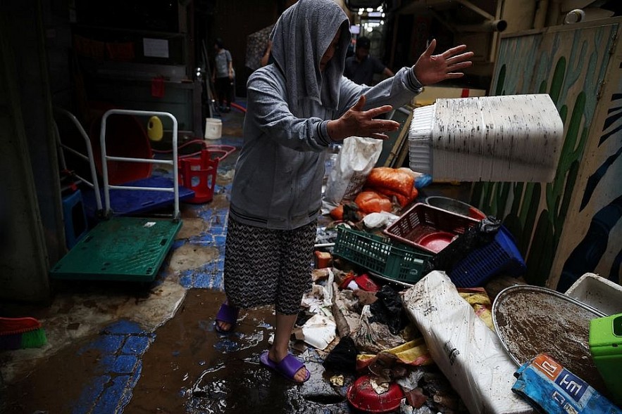 Kim Sun-ok cleans up debris from her restaurant damaged by flood after torrential rain at a traditional market in Seoul, South Korea, August 9, 2022. REUTERS/Kim Hong-Ji