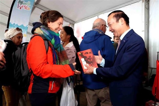 Vietnamese Ambassador to Belgium Nguyen Van Thao presents a book about late President Ho Chi Minh to a foreign reader at Manifesta 2022. Photo: VNA