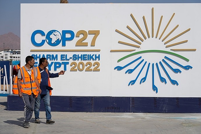 Workers pass by a sign at the convention center hosting the COP27 U.N. Climate Summit in Sharm el-Sheikh on Saturday. (Peter Dejong/AP)