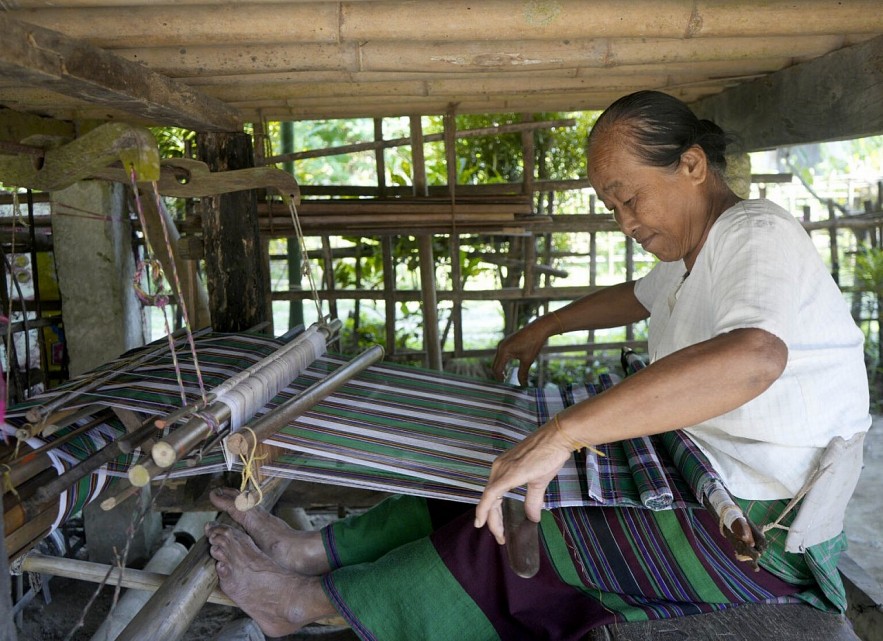 Displaying a Tai Phake woman weaving a traditional costume at her home in Namphake