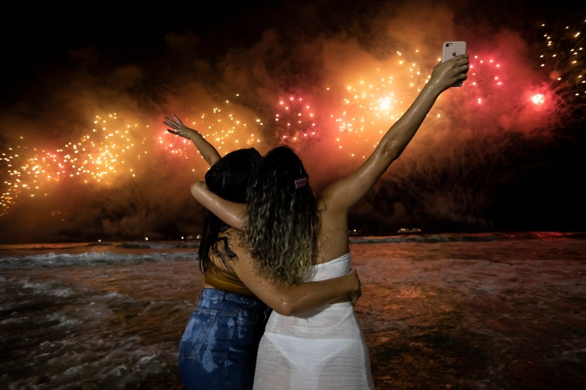 People bring in the New Year as they watch fireworks explode over Copacabana Beach in Rio de Janeiro, Brazil. [Bruna Prado/AP Photo]