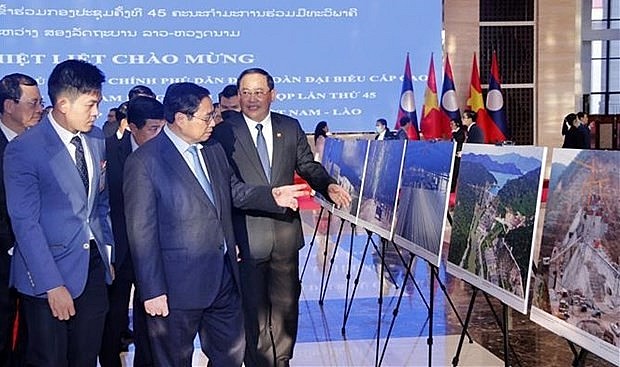 Prime Ministers Pham Minh Chinh (L) and Sonexay Siphandone visit the photo exhibition in Vientiane on January 12. Photo: VNA