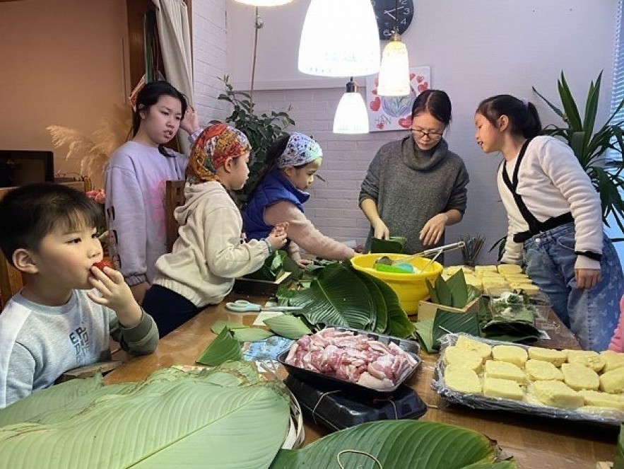 Children learn to make 'banh chung' (square glutinous rice cake), a traditional dish of Vietnamese people during the Tet (Lunar New Year) festival. Photo: VNA