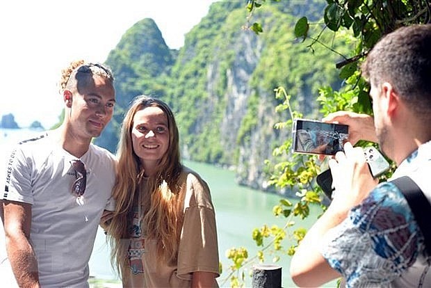 Foreign tourists pose for pictures at Ha Long Bay in the northeastern of Quang Ninh. (Photo: VNA)