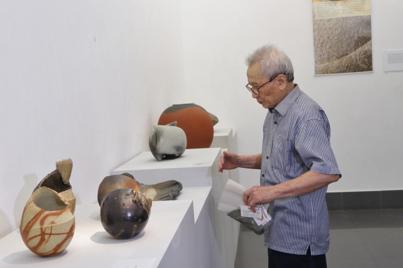 Painter Le Ngoc Han examines the works at the exhibition. Photo: Hanh Tran