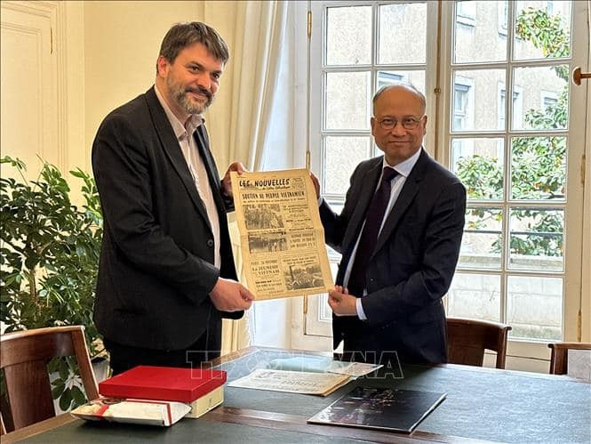 Deputy Mayor of Nantes city Aymeric Seassau (L) presents Ambassador Dinh Toan Thang with the original versions of two local newspapers that were issued in November 1968 and featured articles showing support for Vietnam in the fight against the US imperialists. Photo: VNA