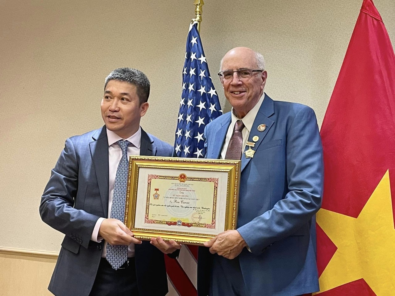 VUFO Vice President and General Secretary Phan Anh Son (L) presents the insignia to Ron Carver, a social activist for peace and a scholar who participated in demonstrations demanding an end to the American war in Vietnam. Source: Ron Carver