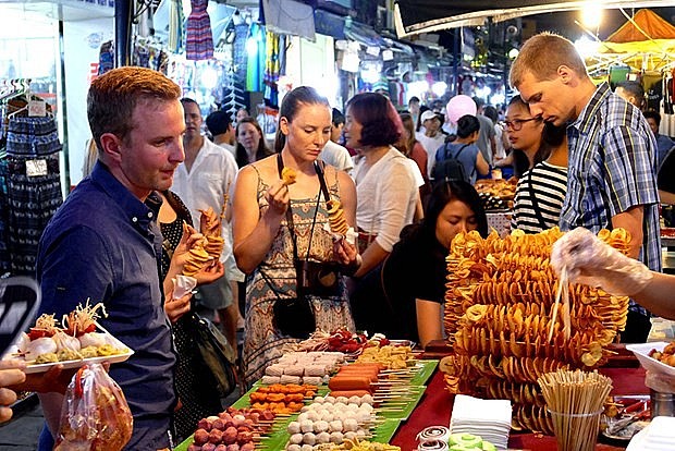 Foreign visitors enjoy street foods at Hanoi's night market. (Photo: thanhnien.vn)