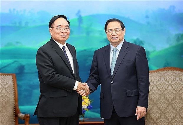 Prime Minister Pham Minh Chinh (R) shakes hands with Lao Minister of Planning and Investment Khamchen Vongphosy. (Photo: VNA) 