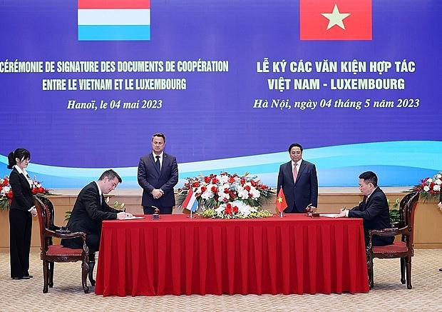 Vietnamese PM Pham Minh Chinh (second from right) and his Luxembourg counterpart Xavier Bettel (centre) witness the signing of the agreement on the strategic partnership in green finance in Hanoi on May 4, 2023. (Photo: VNA)