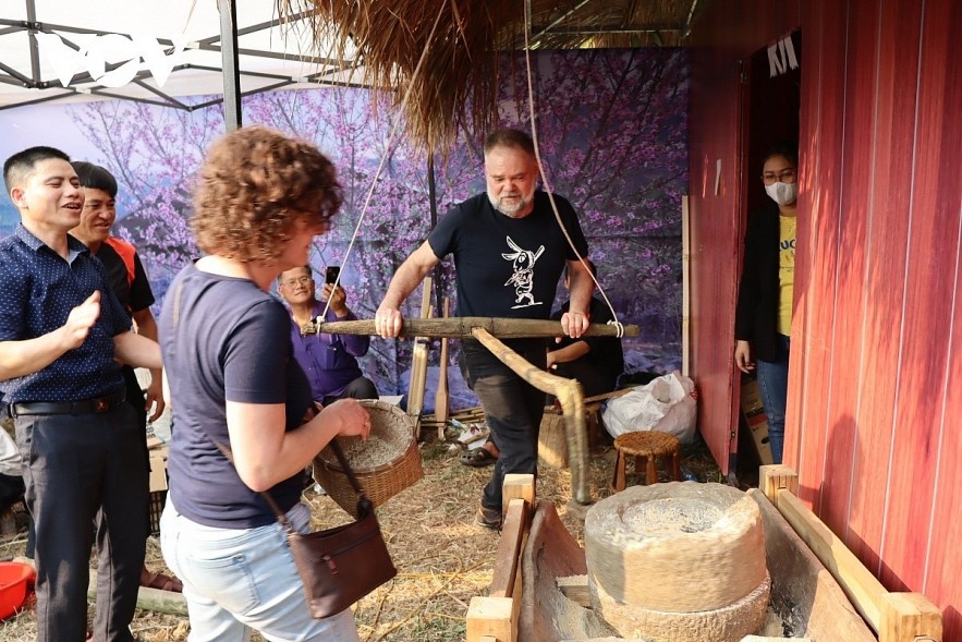 Foreign tourists try pounding rice in the northern mountainous area of Vietnam.