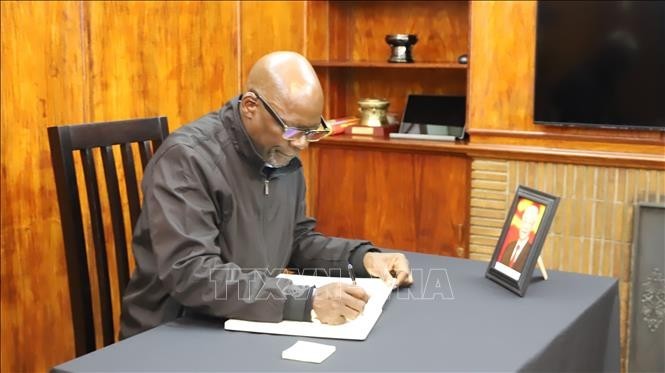 General Secretary of the South African Communist Party Solly Mapaila writes in the condolence book. (Photo: VNA) 