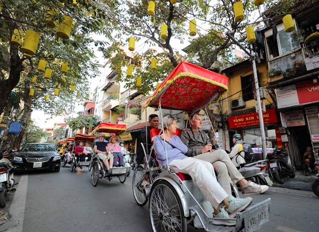 Foreign tourists ride pedicabs around the streets, enjoying the beauty of Hanoi. (Photo: VNA)