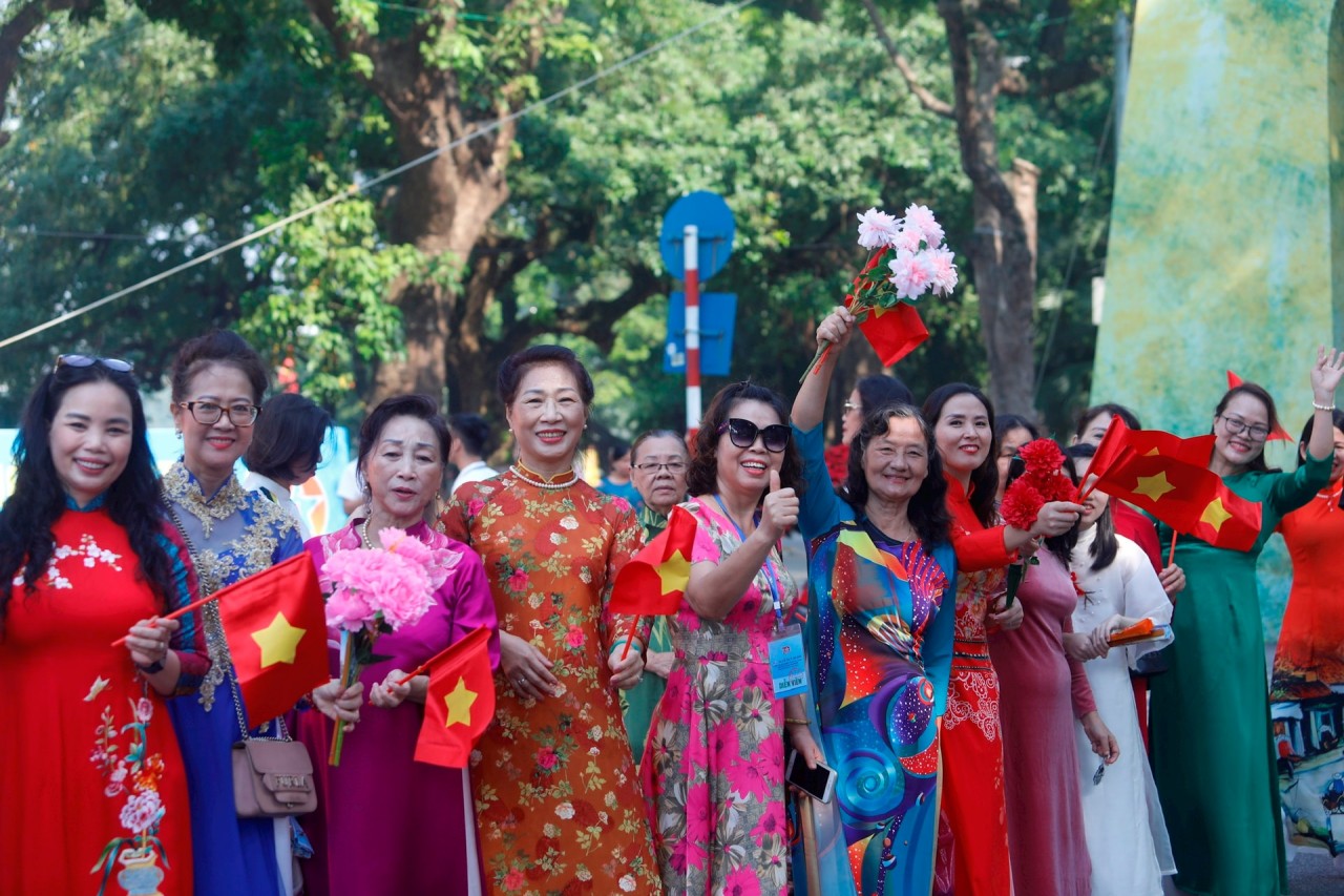 Many citizens wear traditional ao dai, waving flags and flowers, sharing their pride as they witnessed the reenactment of historical milestones in the capital during the festival. (Photo: Ha Noi Moi Newspaper)