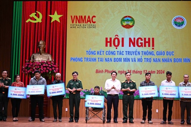 Representatives of the Việt Nam National Mine Action Centre give presents to mine victims in Bình Phước Province. — Photo courtesy of the VNMAC