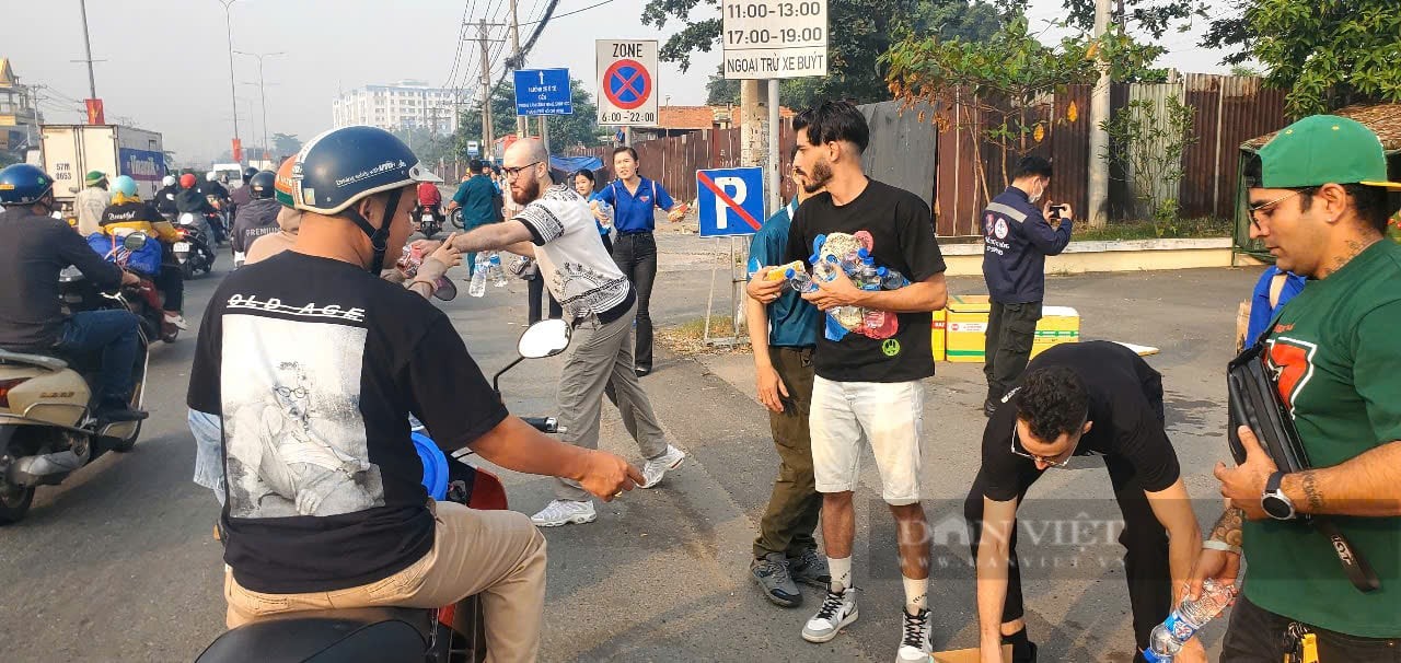 Foreigners enthusiastically gave away tens of thousands of bottles of mineral water to people returning home to celebrate Tet At Ty, District 12. (Photo: Chinh Hoang/Dan Viet Newspaper)