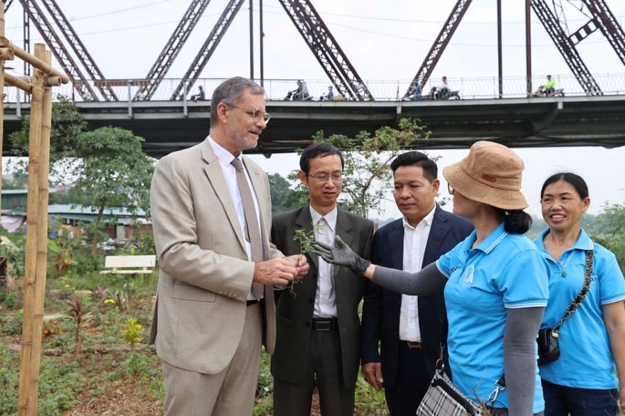 The French Ambassador engages in discussions with residents about the playground located at the base of Long Bien Bridge and the various plants and herbs cultivated nearby.