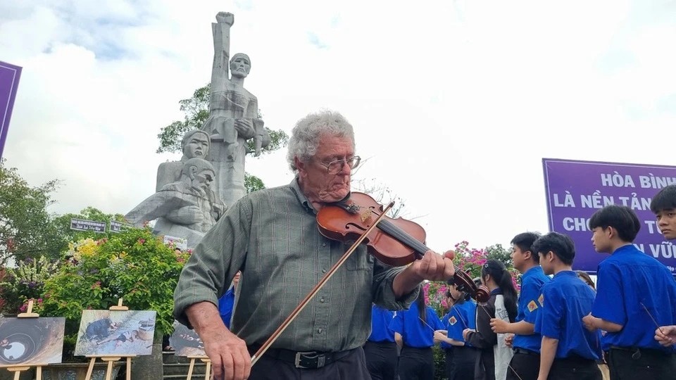 Mike Boehm plays his violin under the Son My Memorial statue. (Photo: Znews)