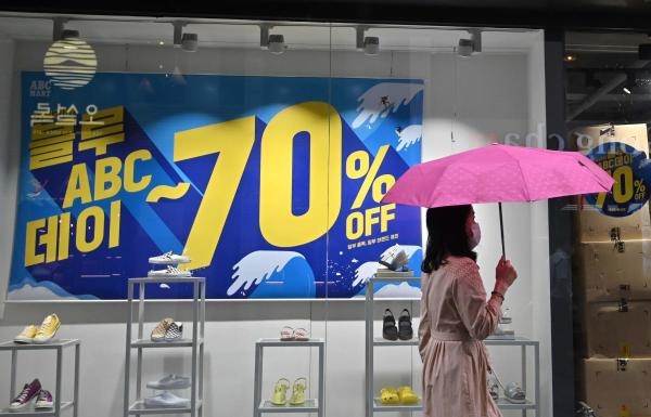 A woman walks past a commercial sign at a shopping district in Seoul on July 23, 2020