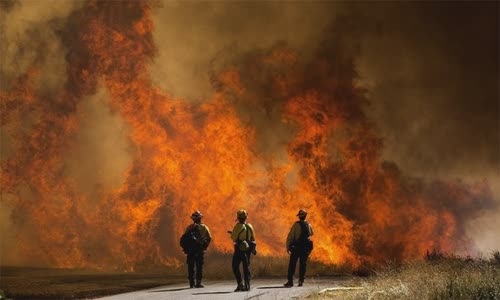 Firefighters look at the fire of an Apple fire in Cherry Valley, California, on August 1 