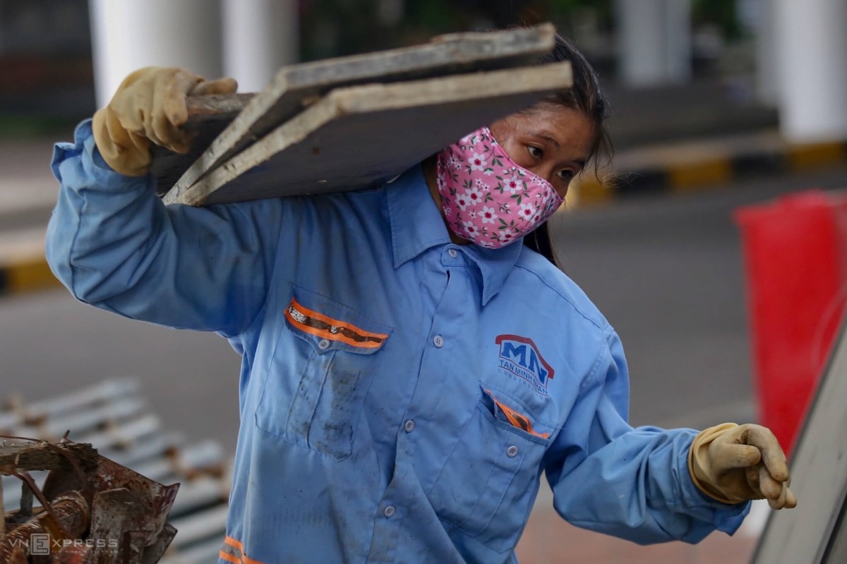 A worker carries a stack of sheets on her shoulders.