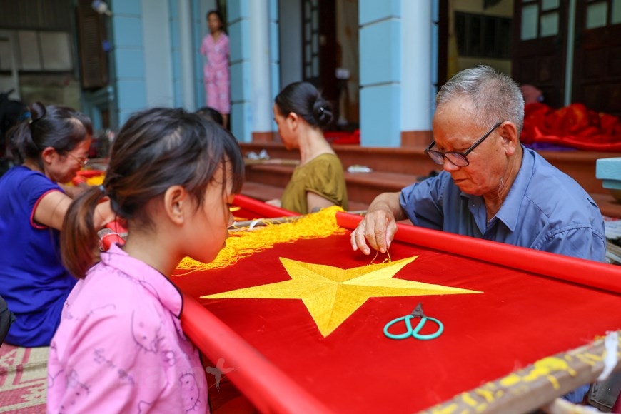 A family of three generations in Tu Vu villge is weaving the flags