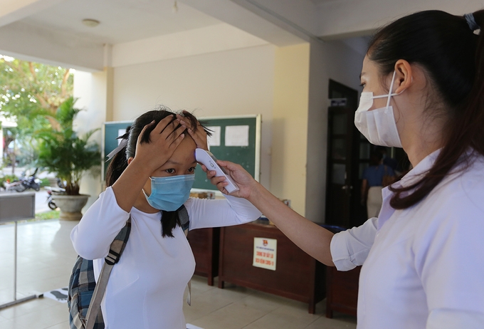 One student is checked for body temperature