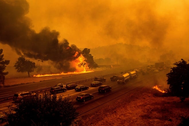 Flames from the LNU Lightning Complex fires jump Interstate 80 in Vacaville, Calif., Aug. 19, 2020. The highway was closed in both directions shortly afterward.