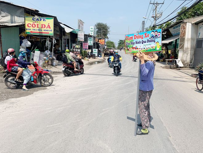 62-year-old lady holds traffic sign to help students pass the road in Ho Chi Minh city, video