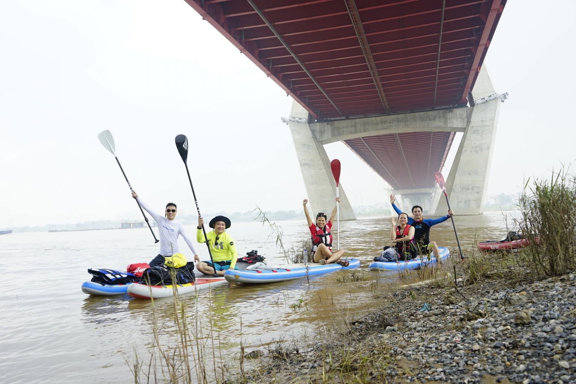 Young people in Hanoi try paddle boarding on Red river
