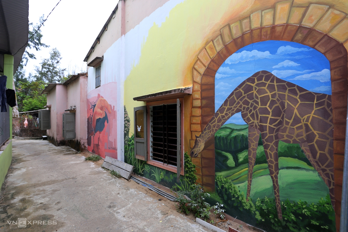 The wall of a narrow alley is covered with murals.