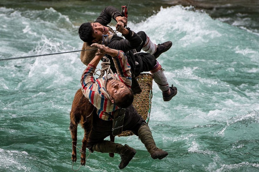 Two men use a zipline to transport animals and good across the river in Yunnan, China, May 2021. Photo by Minqiang Lu/The Nature Conservancy