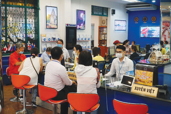 Local residents look for summer tours at a travel agency. Photo courtesy of nld.com.vn