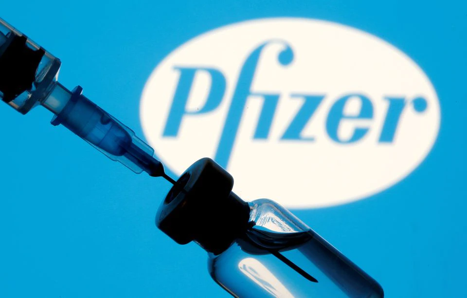 A vial and syringe are seen in front of a displayed Pfizer logo in this illustration taken January 11, 2021. REUTERS/Dado Ruvic/Illustration