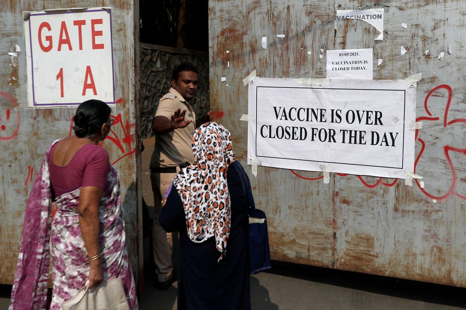 A policeman asks people who came to receive a dose of a coronavirus disease (COVID-19) vaccine to leave as they stand outside the gate of a vaccination centre which was closed due to unavailability of the supply of COVID-19 vaccine, in Mumbai, India, May 3, 2021. REUTERS/Francis Mascarenhas