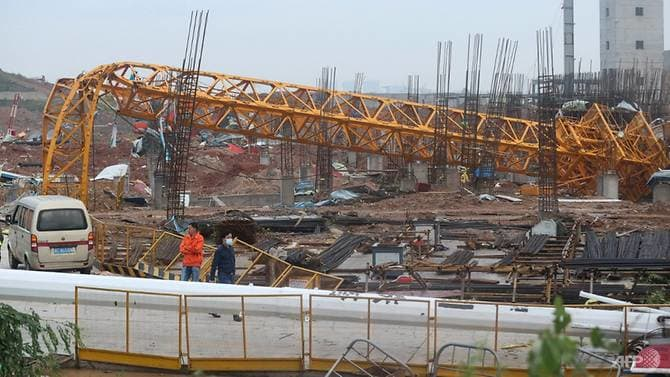 People stand near a toppled crane at a construction site after a tornado hit an economic zone in Wuhan in China's central Hubei province on May 15, 2021. (Photo: AFP)