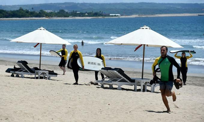 Tourists return from surfing at Kuta beach in Bali Island, Indonesia, February 2020. Photo by AFP.