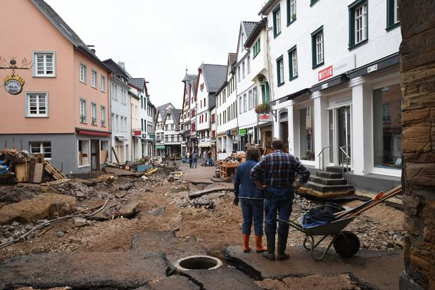 A man and a woman stand with a wheelbarrow as they look at the destroyed pavement of the pedestrian zone in Bad Muenstereifel, western Germany, on July 16, 2021. INA FASSBENDER/AFP VIA GETTY IMAGES