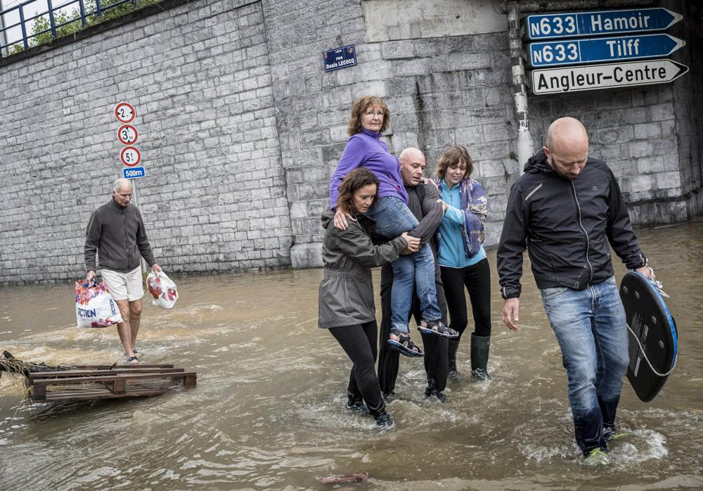 A woman is carried through a flooded street in Angleur, Province of Liege, Belgium, Friday July 16, 2021. Severe flooding in Germany and Belgium has turned streams and streets into raging torrents that have swept away cars and caused houses to collapse. (AP Photo/Valentin Bianchi)