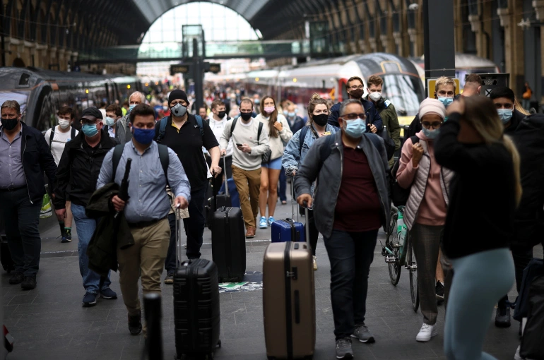 People wearing protective face masks walk along a platform at King’s Cross Station, amid the coronavirus disease (COVID-19) outbreak in London [File: Henry Nicholls/Reuters]