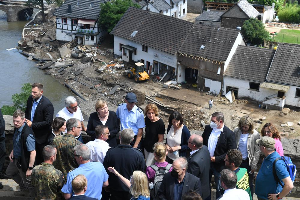 German Chancellor Angela Merkel, rear third left, and the Governor of the German state of Rhineland-Palatinate, Malu Dreyer, rear fifth left, are seen on a bridge in Schuld, western Germany, Sunday, July 18, 2021 during their visit in the flood-ravaged areas to survey the damage and meet survivors. Photo: AP 