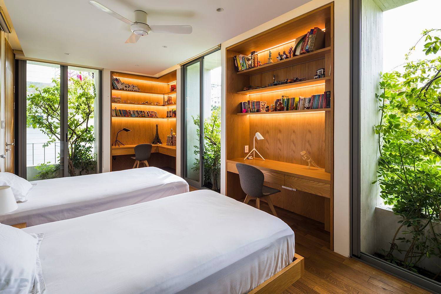 The bedrooms are greened by more than wooden shelves and the usual potted plants. Vines and trees planted just outside glass walls limit provide shade from the sun while providing plenty of natural light.  