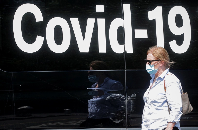 Alarms are sounding in the United States about the spreading Delta variant of the coronavirus as a woman wearing a mask passes by a COVID-19 mobile testing van in New York City on July 22 [Brendan McDermid/Reuters]