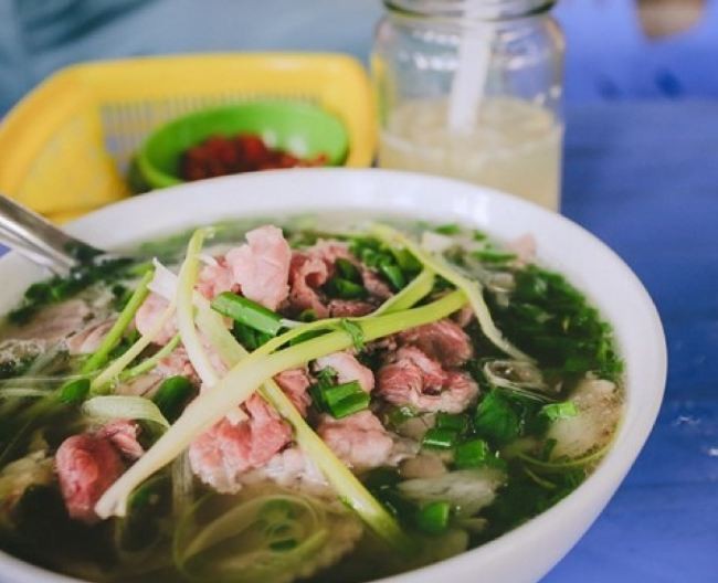 A bowl of “pho” contains flat, soft rice noodles dipped in a fragrant beef or chicken broth flavored with different condiments. It is served with beef or chicken, shallots, and chili and lime to taste.