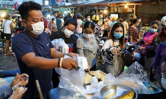 People wearing protective face masks rush to buy groceries at a fresh market amid rumors of a citywide lockdown during the latest Covid-19 outbreak at a temple in Phnom Penh, Cambodia, April 14, 2021. Photo by Reuters/Cindy Liu.