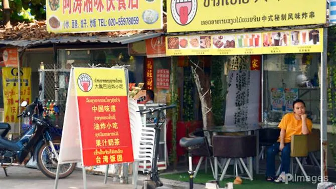 A restaurant clerk rests at a Chinese restaurant in Vientiane on Feb 11, 2020. Laos locked down its capital and closed its international borders to most traffic on Thursday, Apr 22, 2021, after identifying a COVID-19 cluster connected to its bigger neighbour Thailand. (File photo: AP/Kyodo News)