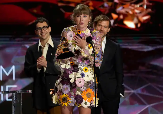 Taylor Swift accepts the award for album of the year for “Folklore” at the 63rd annual Grammy Awards in Los Angeles. In the background are her collaborators, Jack Antonoff, left, and Aaron Dessner. (Chris Pizzello/Invision/AP)